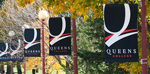 The Queens College Logo Banners on light poles outdoors.