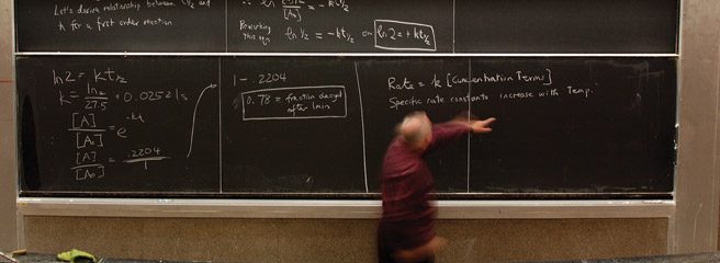 Person pointing at a blackboard.