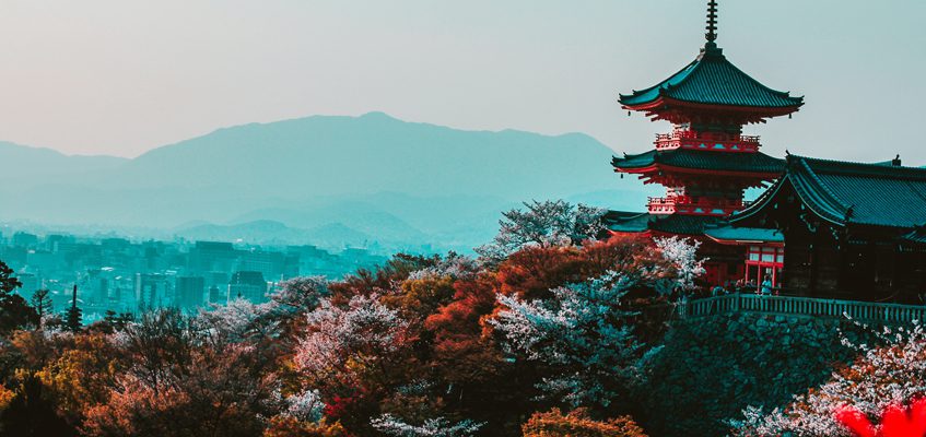 Anthropology. A temple in the distance surrounded by trees. A temple in the distance surrounded by trees. Mountains are visible in the background.