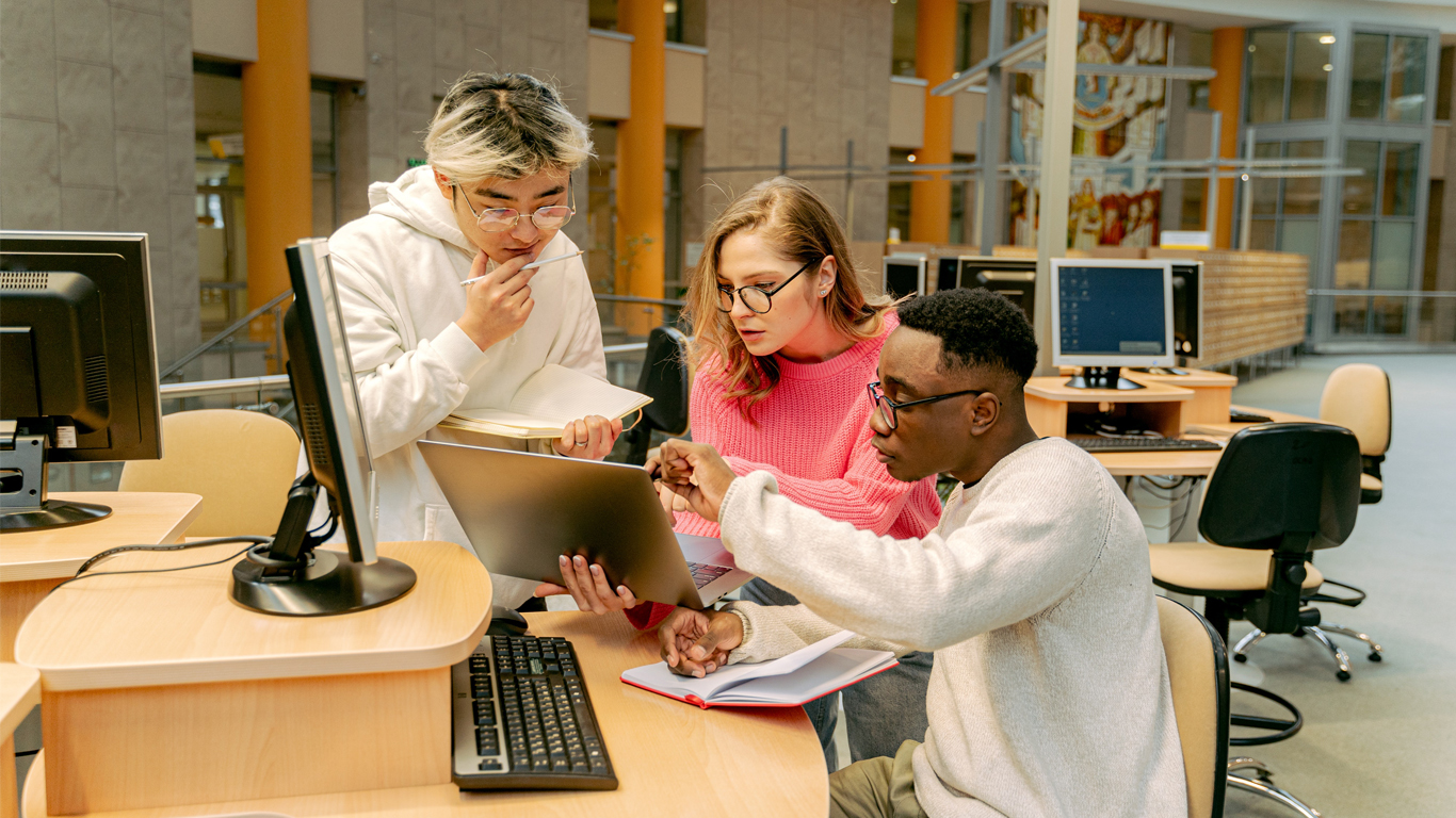 Three people looking at a laptop.