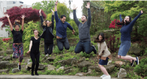 Seven people jumping with joy outside.