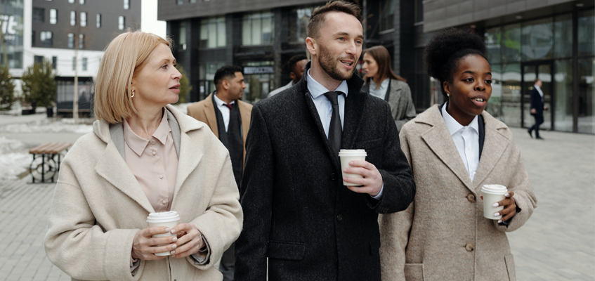 Three people holding coffees and walking together.