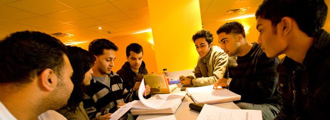 A group of people sitting a table studying.