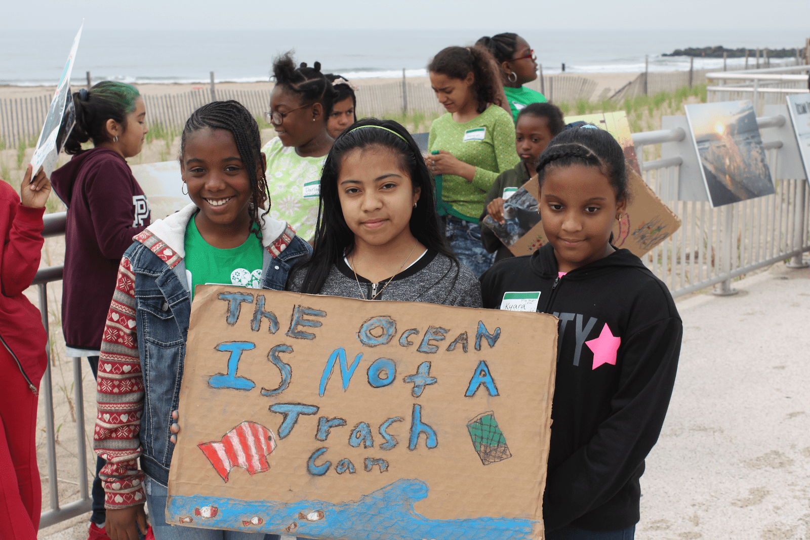 Three children holding a sign that reads: the ocean is not a trash can.
