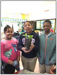 Students holding a planter made from a repurposed plastic soda bottle.