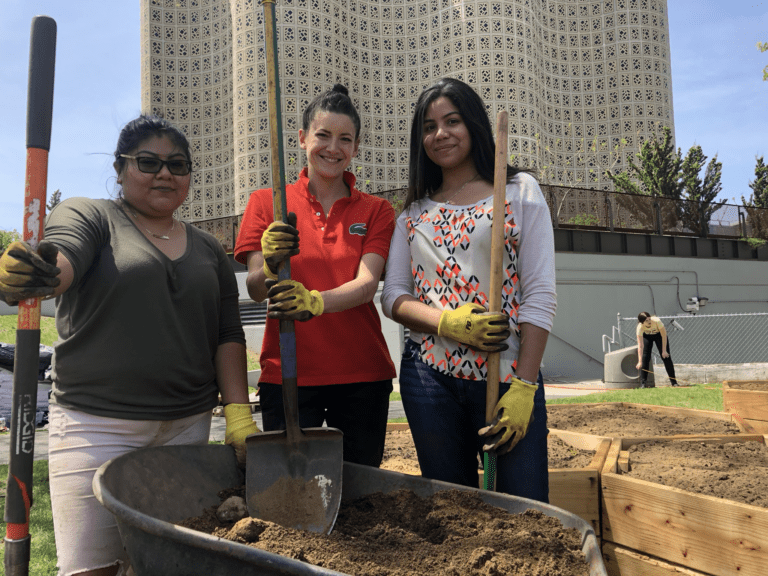 Three people holding shovels.