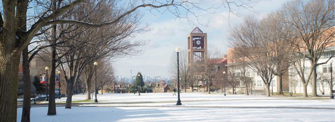A view of Queens College Campus during the winter. The ground is lightly covered in snow.