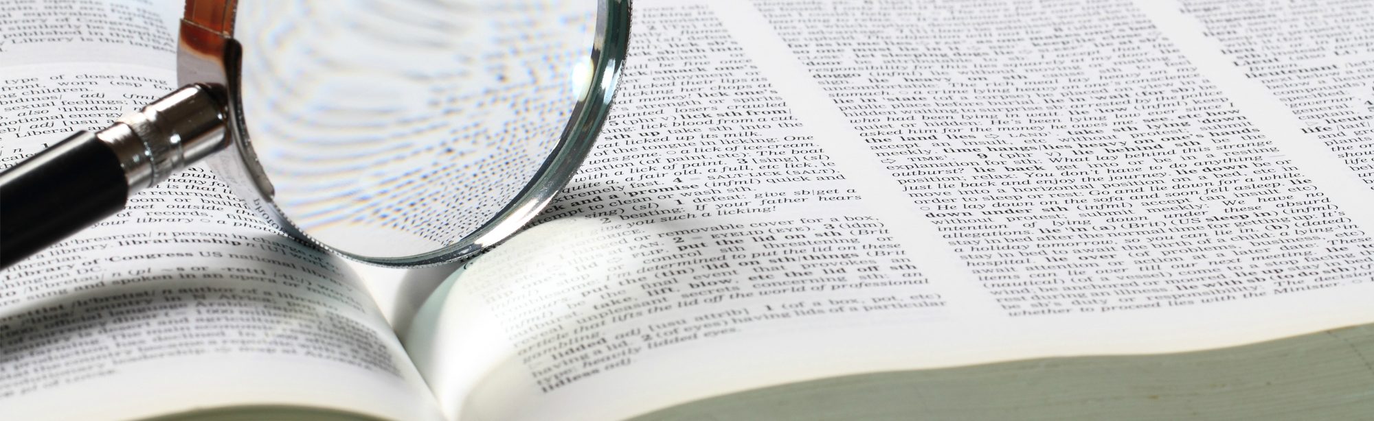 A magnifying glass balanced on an open book. A magnifying glass balanced on an open book.