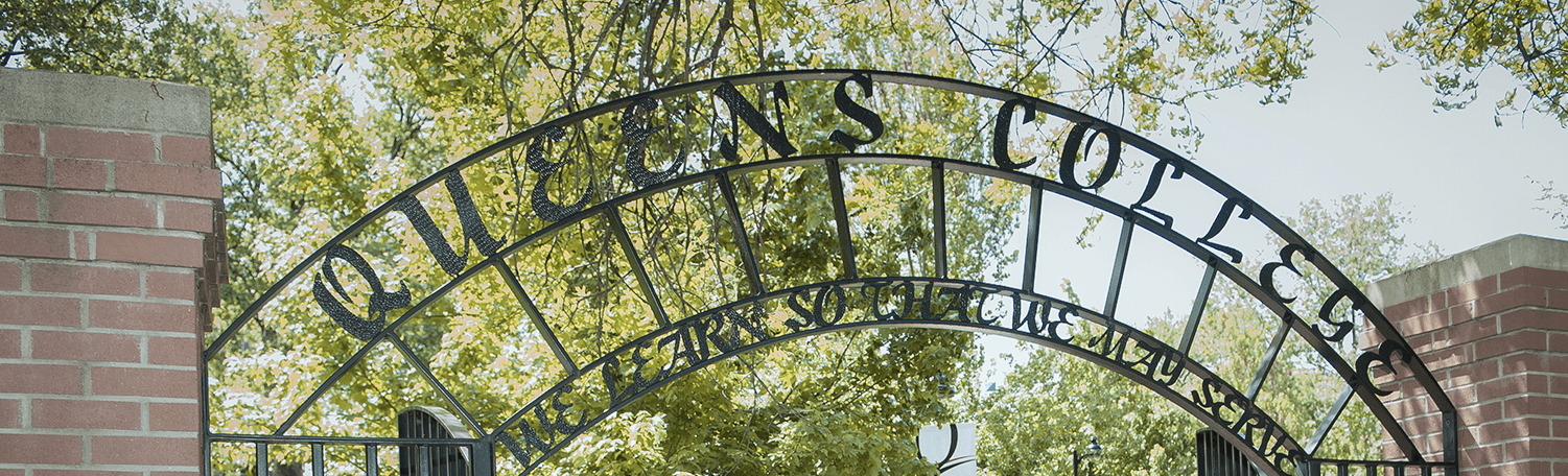 A close-up of the arch of the Queens College entrance. The archway reads Queens College We learn so that we may serve.