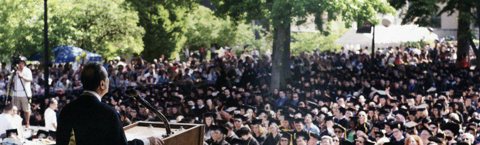 A person standing at a podium giving a speech to graduates.