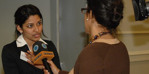 An interviewer holds a microphone towards Aniqa Islam.
