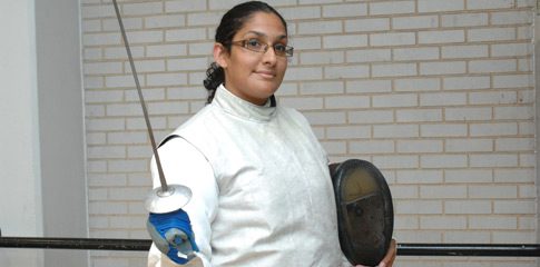 Erika Matos wearing fencing uniform and holding a fencing weapon.