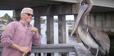 John Waldman poses for the photo with a pelican.