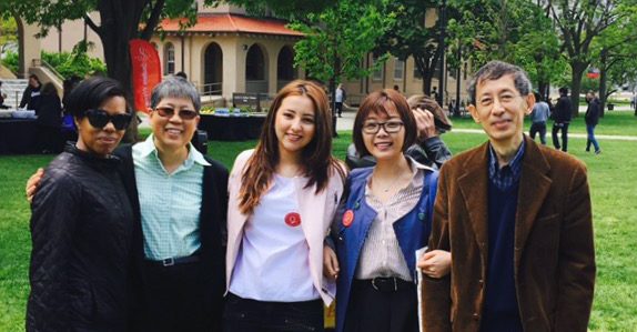 Five people standing outdoors side-by-side at Queens College Campus.