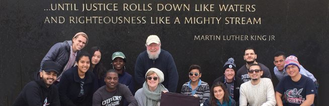 A group photo of the “Footsteps of Dr. King” trip. In the background a quote is written on the wall. It reads “…Until justice rolls down like waters and righteousness like a mighty stream” – Martin Luther King Jr.
