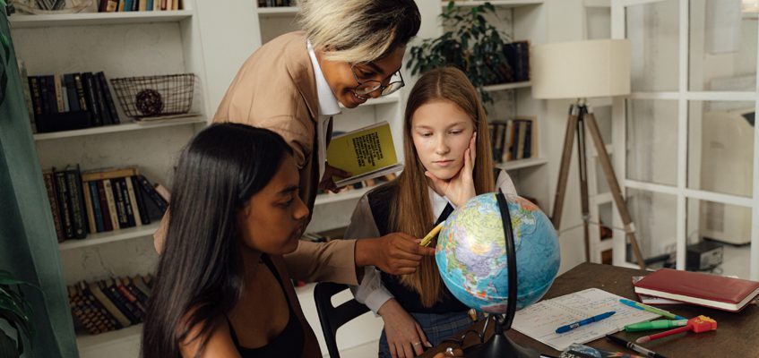 Three people looking at a globe.