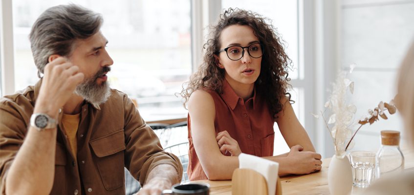 Two people sitting at a table and are having a conversation.