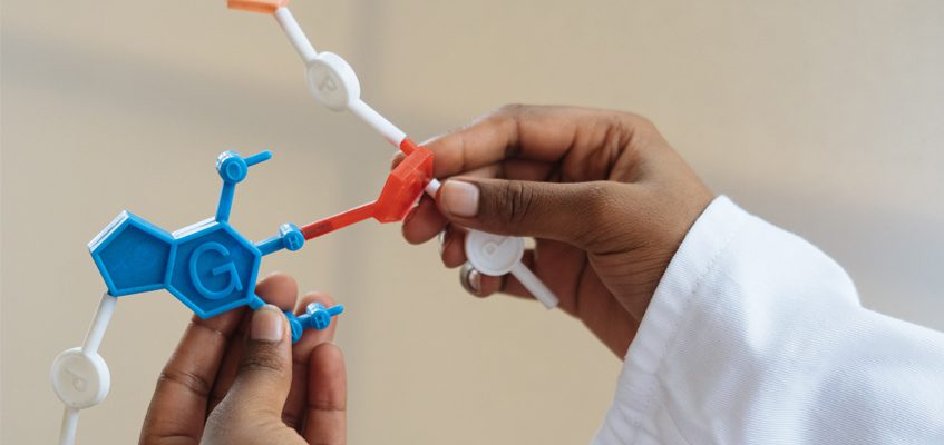 A close-up of a person’s hands holding a molecule model.