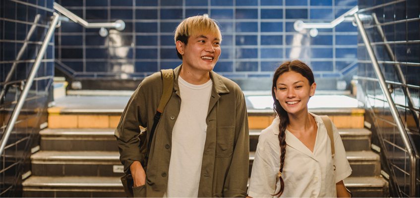 Two people walking down the stairs and towards the camera smiling.