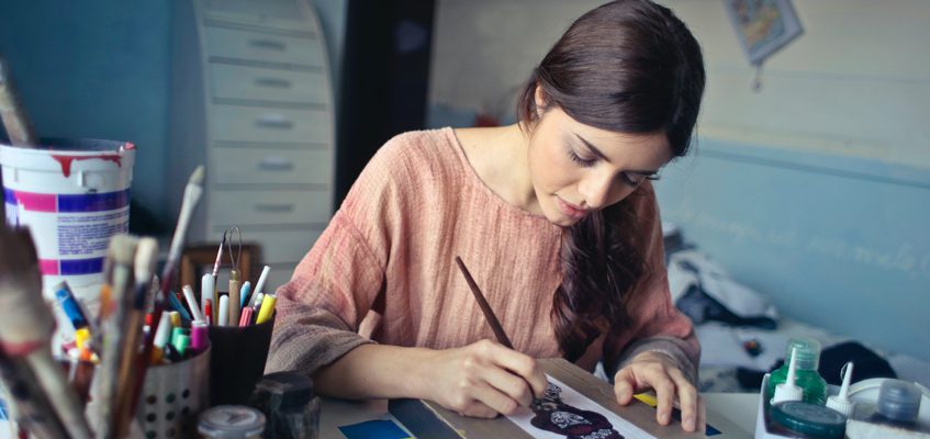 A person sitting at a desk and painting.