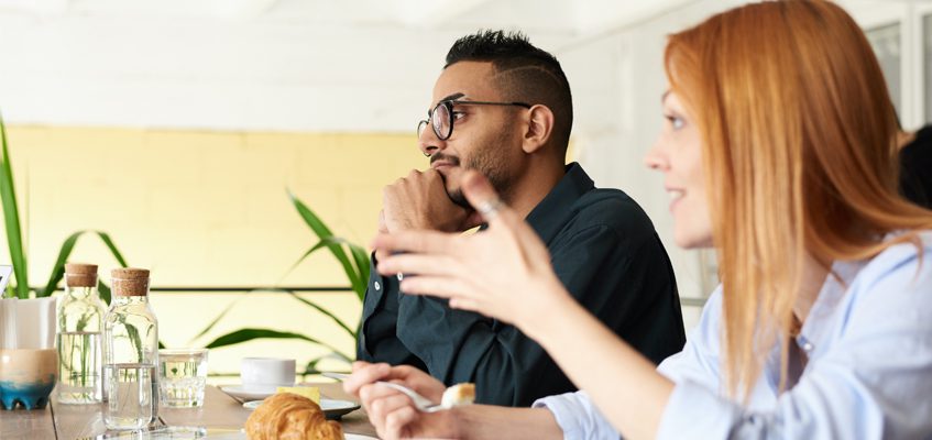 Two people sitting together side-by-side and talking.