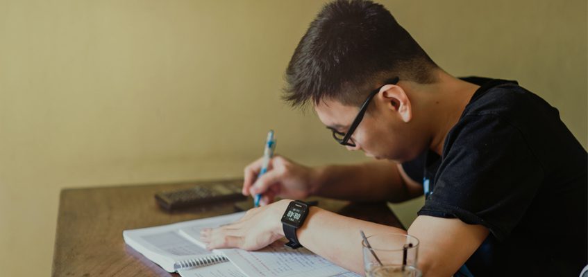 A person at a desk writing down notes in a notebook. 