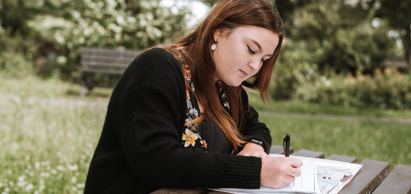 A person sitting at a table and writing. 