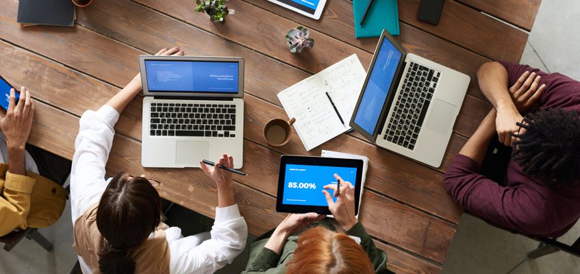 An overhead shot of a group of people working on either a laptop or a tablet.