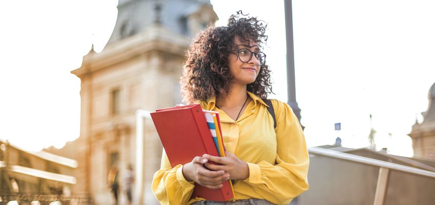 A woman standing and holding books.