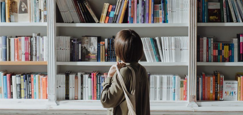A person looking at a bookshelf.