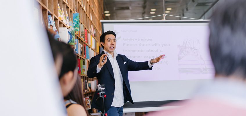 A lecturer standing in front of a class teaching.