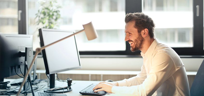A man smiling and working on a computer.