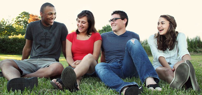 Four people sitting on the grass together.