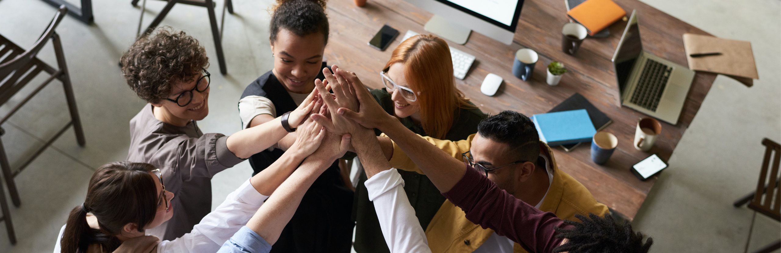 Eight people standing in a circle high fiving.