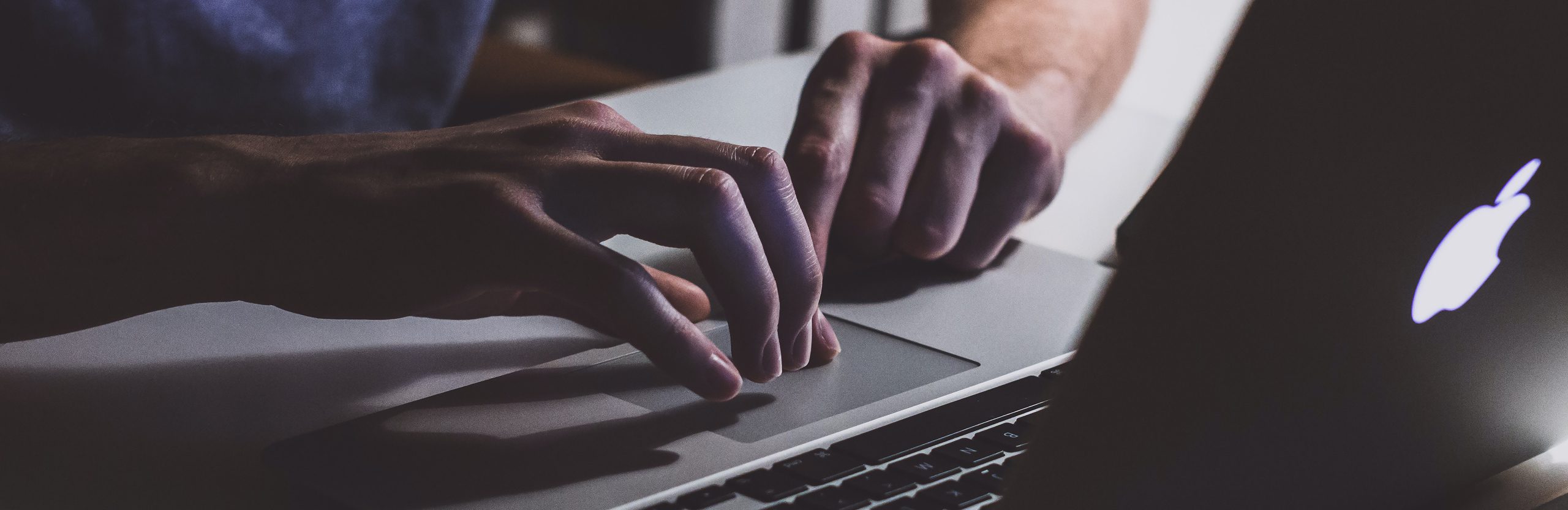 A person’s fingers touching the track pad on a laptop.