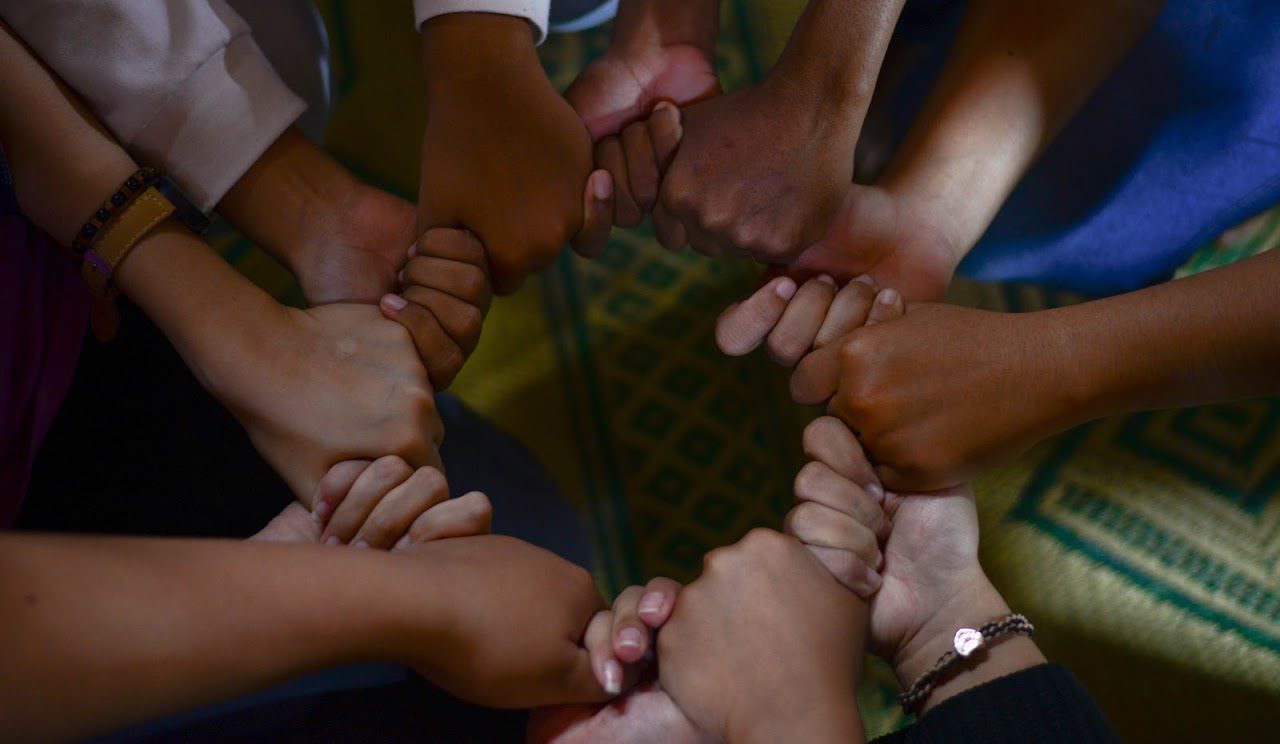 A close-up of people’s hands linked together in a circle.