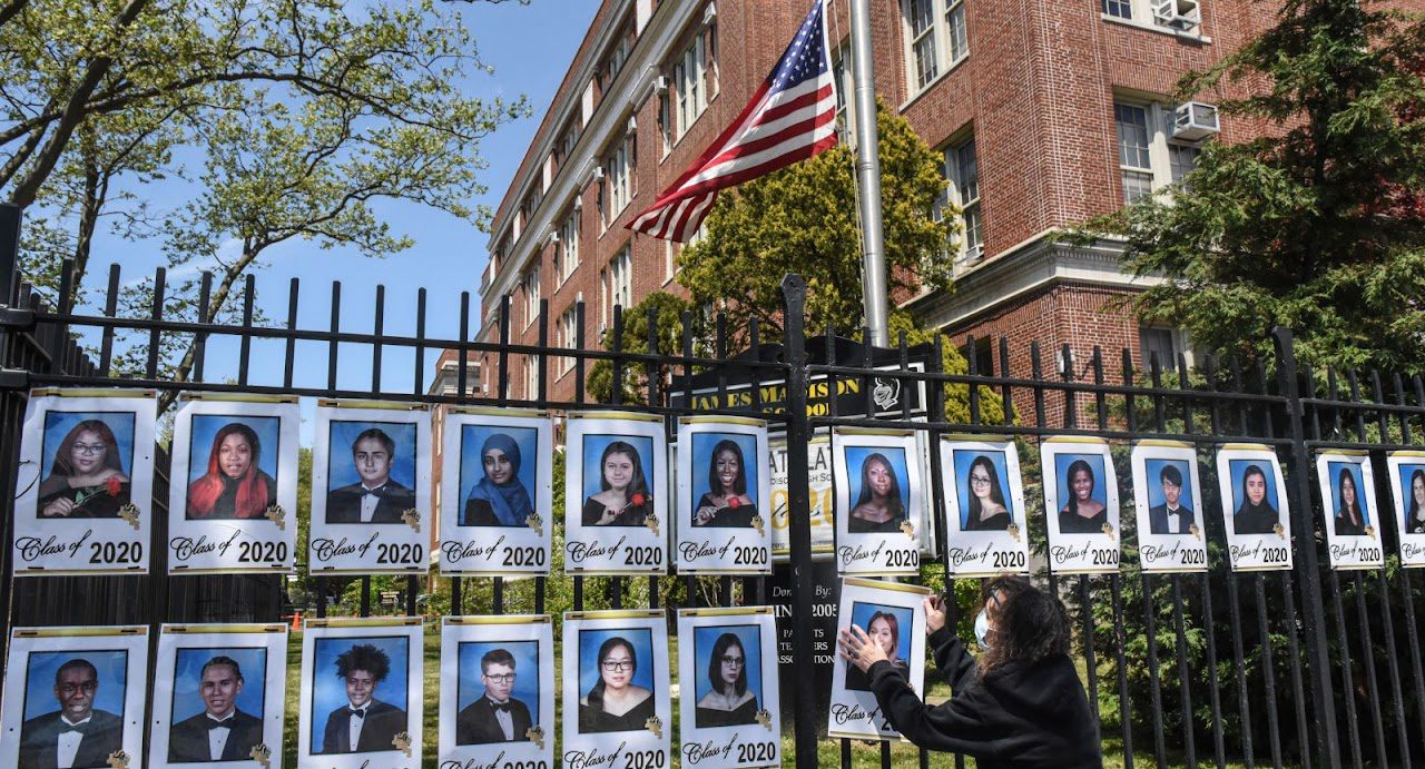 Luz Carlson hangs up photos of all the graduating seniors outside of James Madison High School in New York on May 14.
