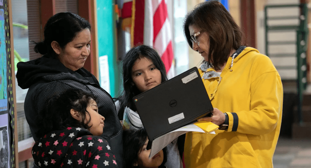 Teacher Maria Sanislo (right) explains a Google Chromebook to a family at KT Murphy Elementary School in Stamford, Connecticut, March 17.