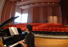 A man playing the piano in the Choral Room.