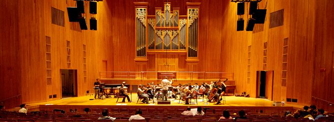 A view of The LeFrak Concert Hall with an orchestra playing on stage. 