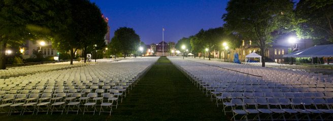 The Quad the night before graduation containing chairs in rows and an aisle in the middle.