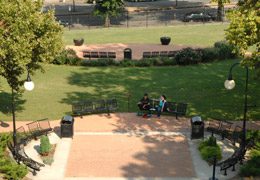 Alumni Plaza-A lawn with paved spaces containing benches.