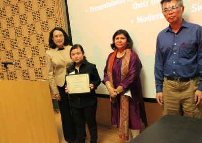 Diana Ng, Junior, Design Major holds up scholarship with three people beside her.
