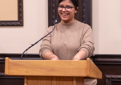 Nabila talking into a microphone on a podium.