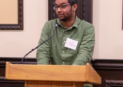 Sagar talking into a microphone on a podium.