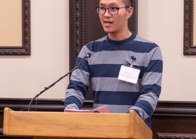 Xincheng talking into a microphone on a podium.