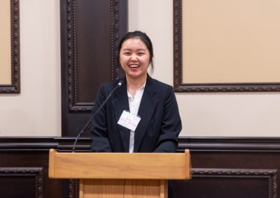 Xinye Feng speaking at a podium.