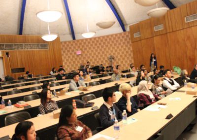 A view of the audience siting down behind desks.