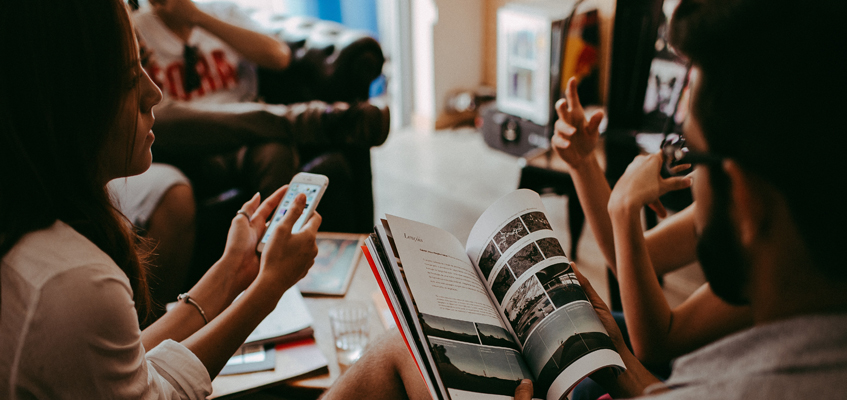 People sitting together holding either smart phones or books.