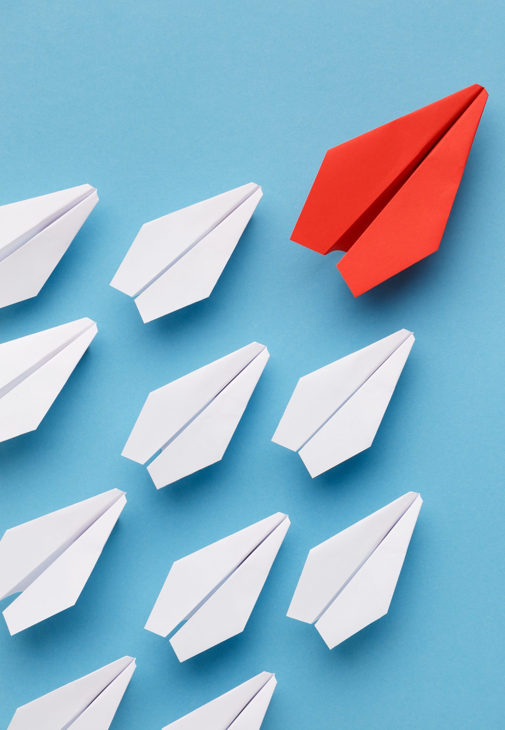 Blue paper boat leading among white ships